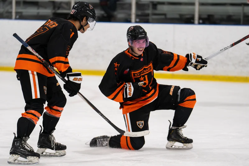 A NY Dynamo hockey player slides on one knee in celebration