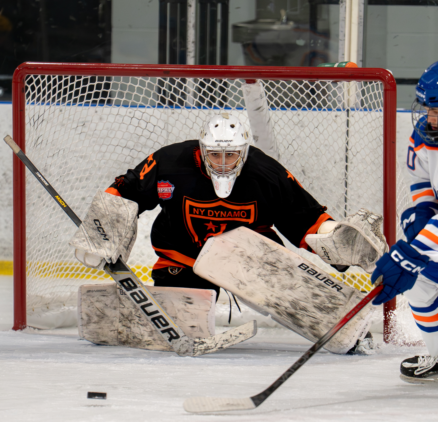 A NY Dynamo goalie, eyes fixed on a moving puck, ready to make the save.