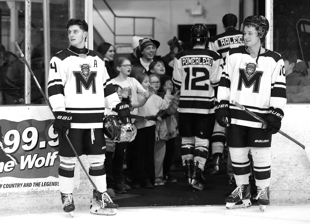 MAINEiacs players high-five young fans leaving the ice after a game